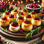 A plate of golden, flaky Cranberry Brie Bites made with puff pastry, melted Brie cheese, and a dollop of cranberry sauce, garnished with fresh rosemary. The setting is warm and festive with scattered cranberries.